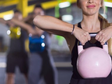 Çapraz fitness stüdyosunda kettlebell egzersizleri yapan bir grup sağlıklı genç sporcu.