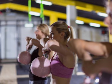 Çapraz fitness stüdyosunda kettlebell egzersizleri yapan bir grup sağlıklı genç sporcu.