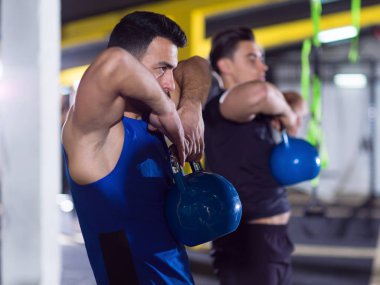 Çapraz fitness stüdyosunda kettlebell egzersizleri yapan bir grup sağlıklı genç sporcu.