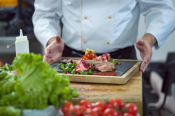 Közelkép a séf kezében szolgáló marha steak — Stock Fotó