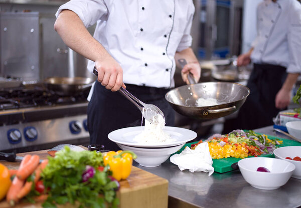 Chef hands serving spaghetti on restaurant kitchen