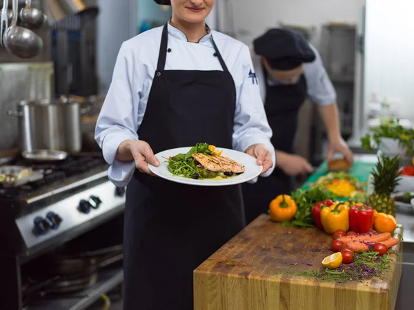 Şef Restoran Mutfağında Sebzeli Kızarmış Somon Balığı Filetosu Tutuyor — Stok fotoğraf