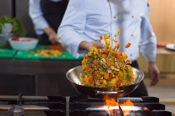 Chef lançando legumes em wok — Fotografia de Stock