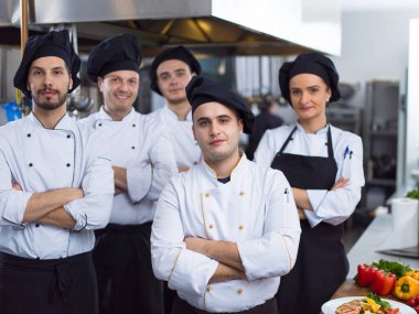 Restoranın ticari mutfağında bir arada duran grup şeflerinin portresi.