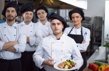 Restoranın ticari mutfağında bir arada duran grup şeflerinin portresi.
