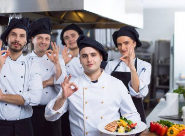 Restoranın ticari mutfağında bir arada duran grup şeflerinin portresi.