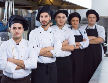 Restoranın ticari mutfağında bir arada duran grup şeflerinin portresi.