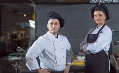 Restorandaki ticari mutfakta yan yana duran iki şefin portresi.