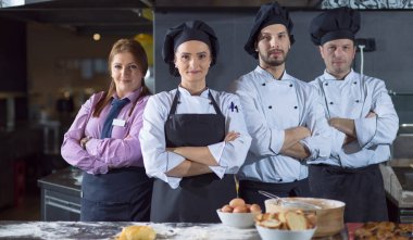 Restoranın ticari mutfağında bir arada duran grup şeflerinin portresi.