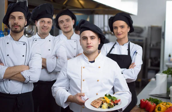 Restoranın ticari mutfağında bir arada duran grup şeflerinin portresi.