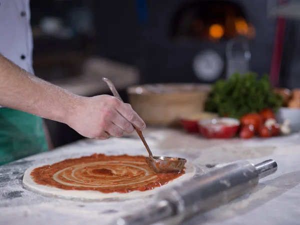 Шеф-повар мажет тесто для пиццы кетчупом — стоковое фото