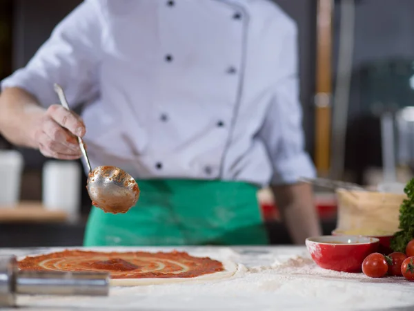 Koch schmiert Pizzateig mit Ketchup — Stockfoto