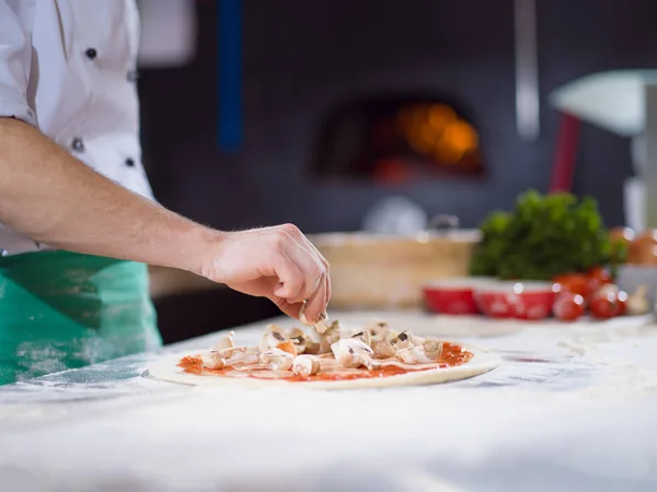 Koch legt frische Pilze auf Pizzateig — Stockfoto