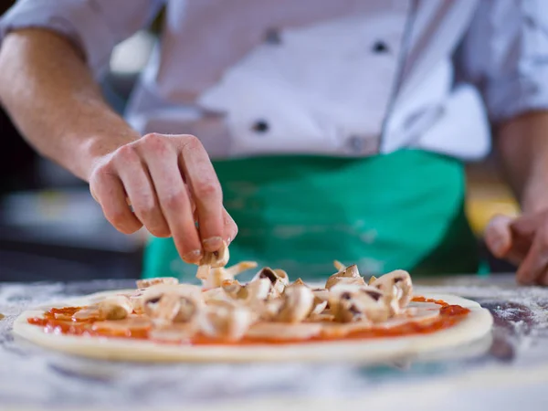 Koch legt frische Pilze auf Pizzateig — Stockfoto