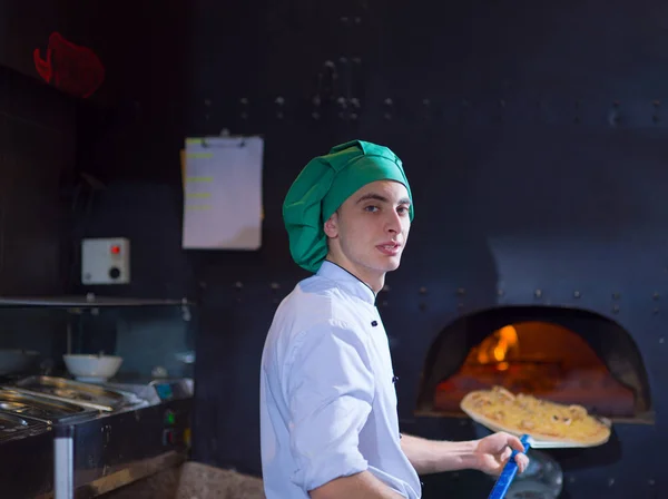 Chef poniendo deliciosa pizza al horno de madera de ladrillo —  Fotos de Stock