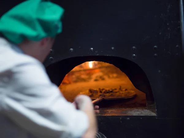 Chef colocando deliciosa pizza para forno de madeira de tijolo — Fotografia de Stock