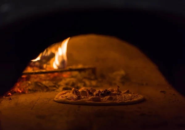 Chef zet heerlijke pizza aan baksteen houtoven — Stockfoto