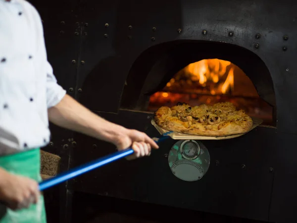 Kuchař, odstranění horké pizza z kamen — Stock fotografie