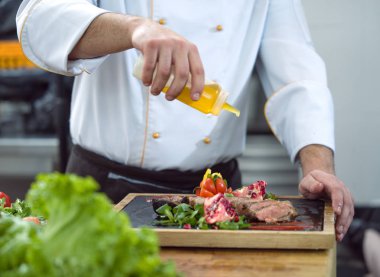 Şef biftek tabağını bitiriyor. Nihayet sosu hazır ve sofrada servis yapmaya hazır.