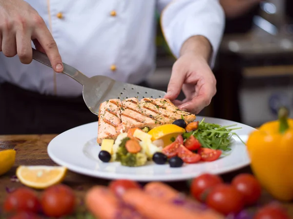 cook chef decorating garnishing prepared meal dish on the plate in restaurant commercial kitchen