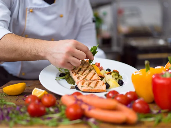 cook chef decorating garnishing prepared meal dish on the plate in restaurant commercial kitchen