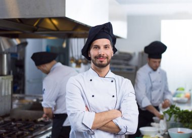 Restoranda ticari mutfakta duran genç aşçının portresi.