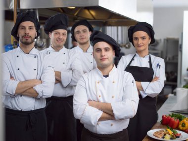 Restoranın ticari mutfağında bir arada duran grup şeflerinin portresi.