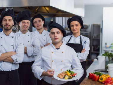 Restoranın ticari mutfağında bir arada duran grup şeflerinin portresi.