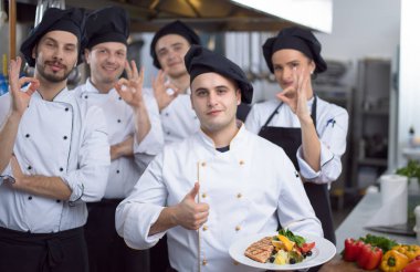 Restoranın ticari mutfağında bir arada duran grup şeflerinin portresi.