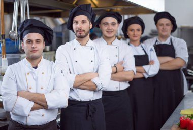 Restoranın ticari mutfağında bir arada duran grup şeflerinin portresi.