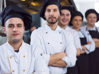 Restoranın ticari mutfağında bir arada duran grup şeflerinin portresi.