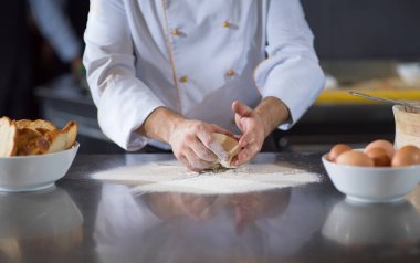 Şef elleri pizza için hamur hazırlarken masaya un serpiştirmiş.