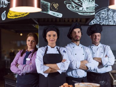 Restoranın ticari mutfağında bir arada duran grup şeflerinin portresi.