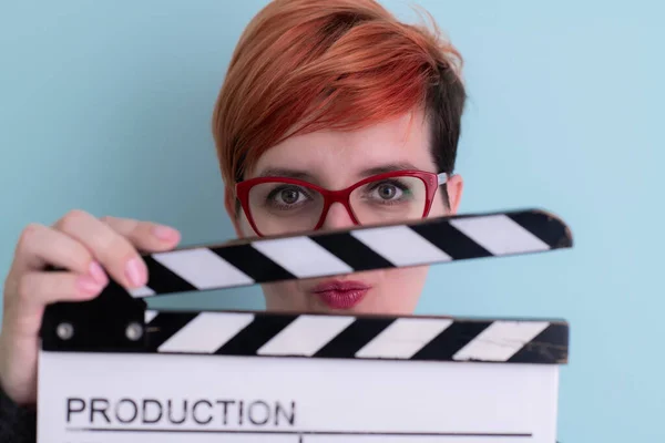 Redhead woman holding movie  clapper on cyan background —  Fotos de Stock