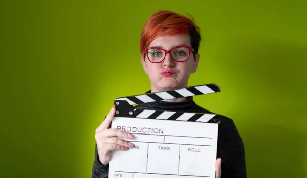 Rossa donna holding film clapper su sfondo verde — Foto Stock