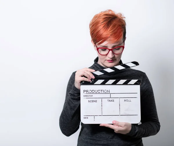 Redhead woman holding movie  clapper on white background — kuvapankkivalokuva