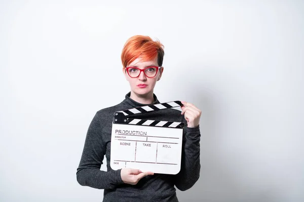 Rossa donna holding film clapper su sfondo bianco — Foto Stock