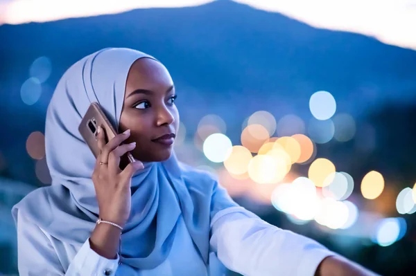 Mujer musulmana joven en la calle por la noche usando el teléfono —  Fotos de Stock