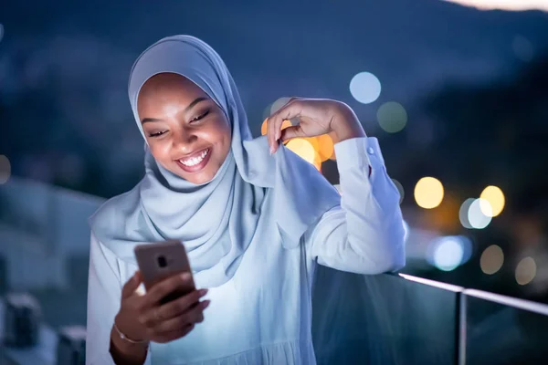 Mujer musulmana joven en la calle por la noche usando el teléfono — Foto de Stock