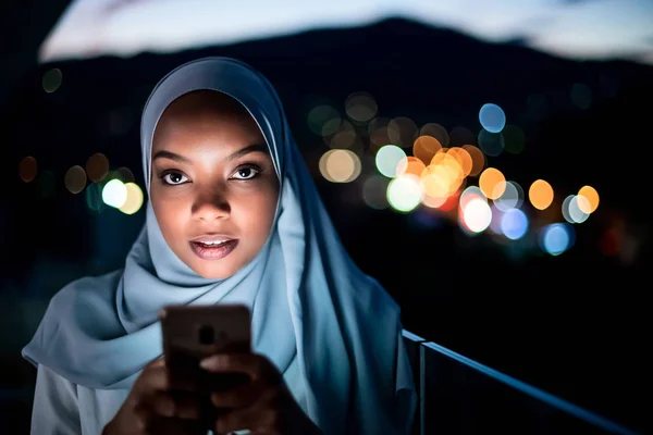 Mladá muslimka na ulici v noci pomocí telefonu — Stock fotografie