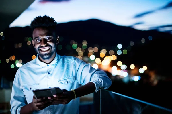 Geceleri sokakta tablet bilgisayar kullanan genç bir afro adam. — Stok fotoğraf