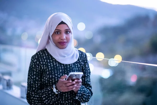 Wanita muslim muda di jalan pada malam hari menggunakan telepon — Stok Foto