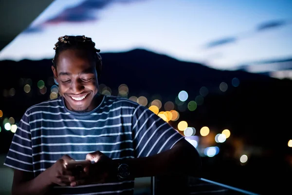 Junger Afro-Mann nachts mit Handy auf der Straße — Stockfoto