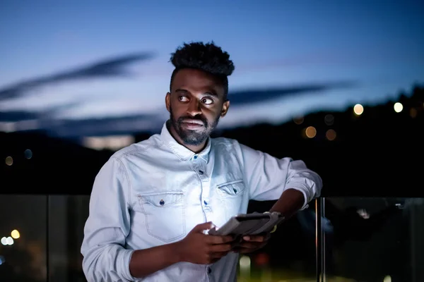 Giovane uomo afro sulla strada di notte utilizzando tablet — Foto Stock
