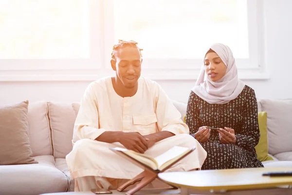 Африканська пара вдома читає Куран — стокове фото