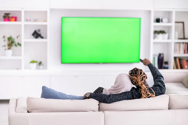 Pareja africana sentada en un sofá viendo televisión juntos —  Fotos de Stock