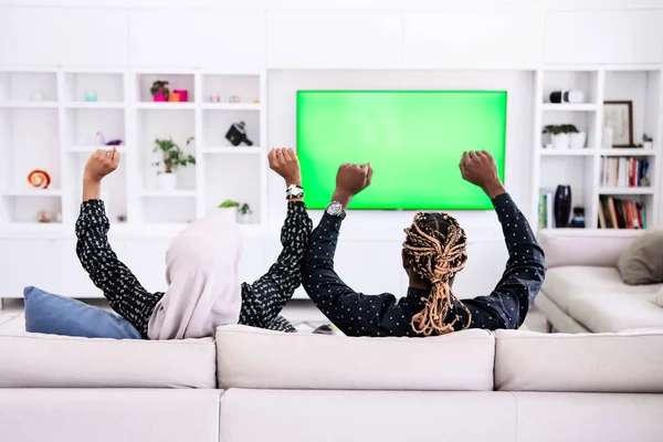 Africký pár sedí na pohovce dívat se spolu na televizi — Stock fotografie