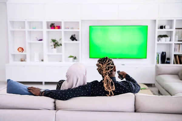 非洲情侣坐在沙发上一起看电视 — 图库照片