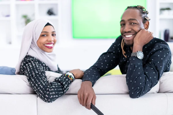 Pareja africana sentada en un sofá viendo televisión juntos —  Fotos de Stock