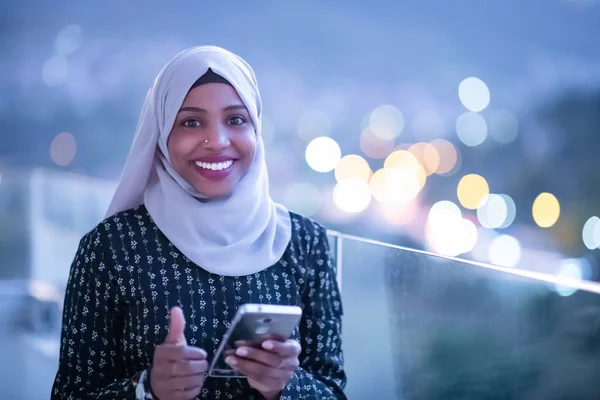 Wanita muslim muda di jalan pada malam hari menggunakan telepon — Stok Foto